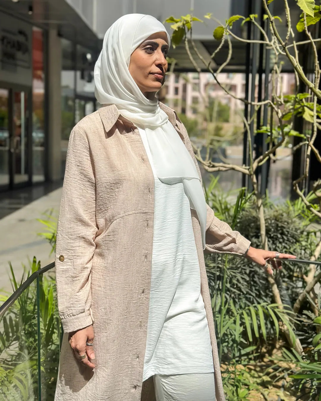 Close-up view of beige modest dress showing straight cut, long sleeves, and lightweight fabric texture