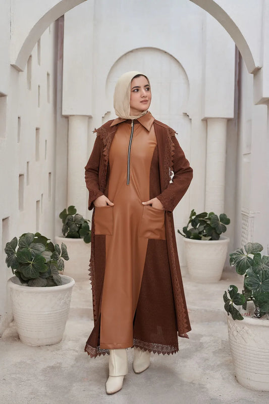 Woman in a brown Leather Dress standing in a decorative archway with plants.
