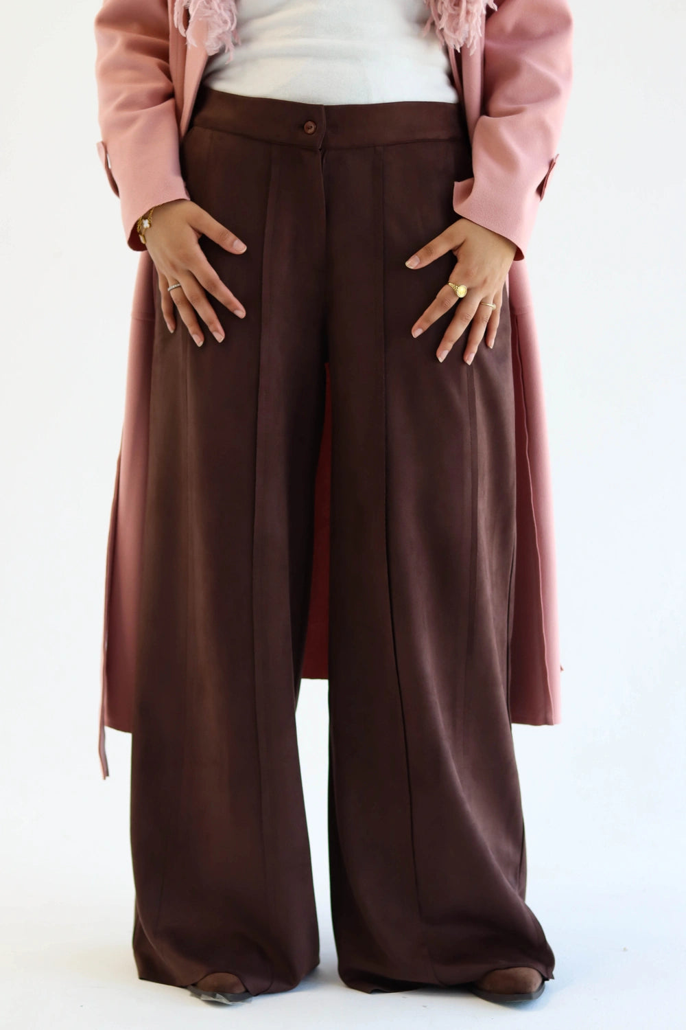 Person wearing brown wide-leg pants with a light pink blazer on a white background