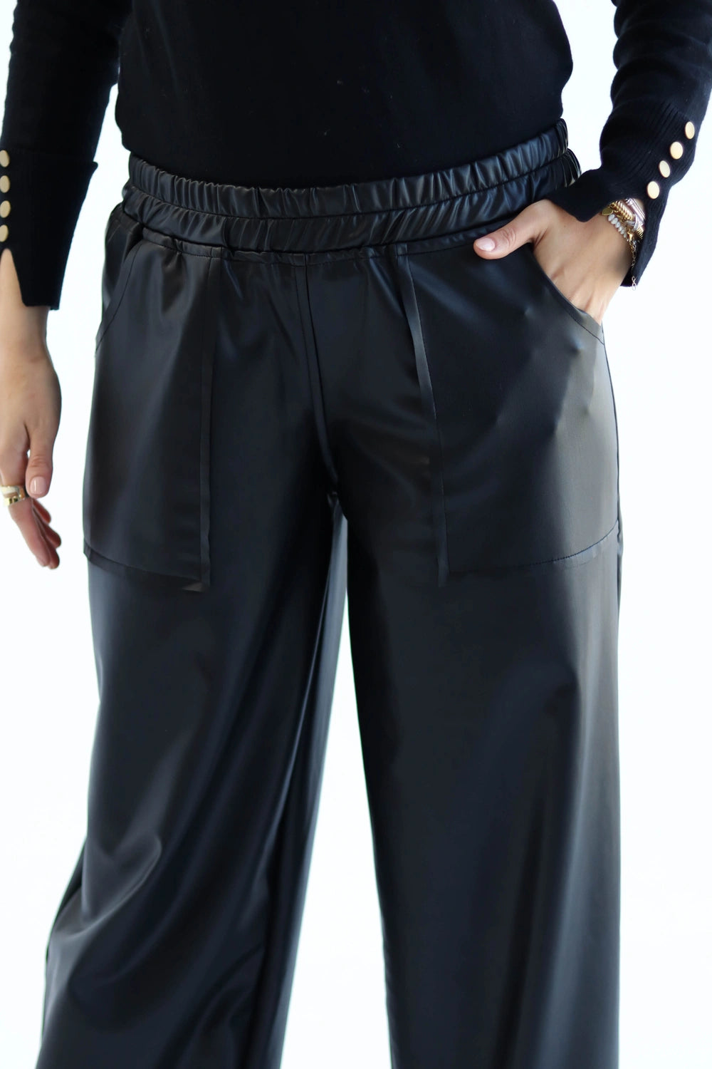 Person wearing black pants with a plain background