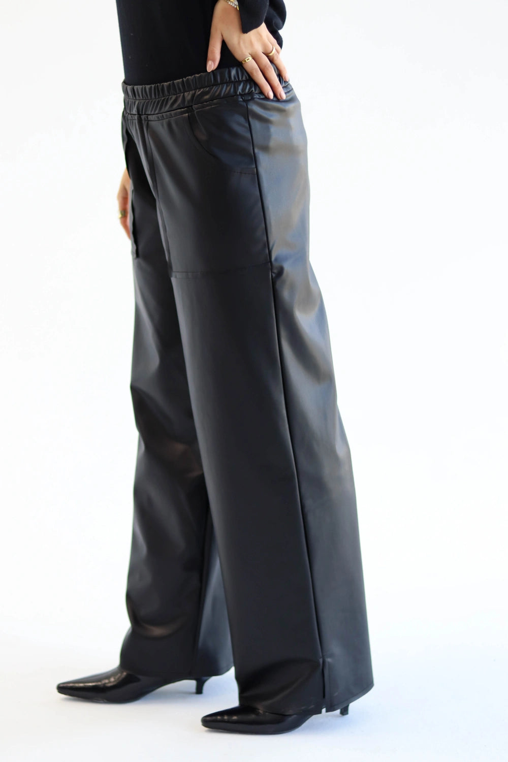 Person wearing black leather pants on a white background