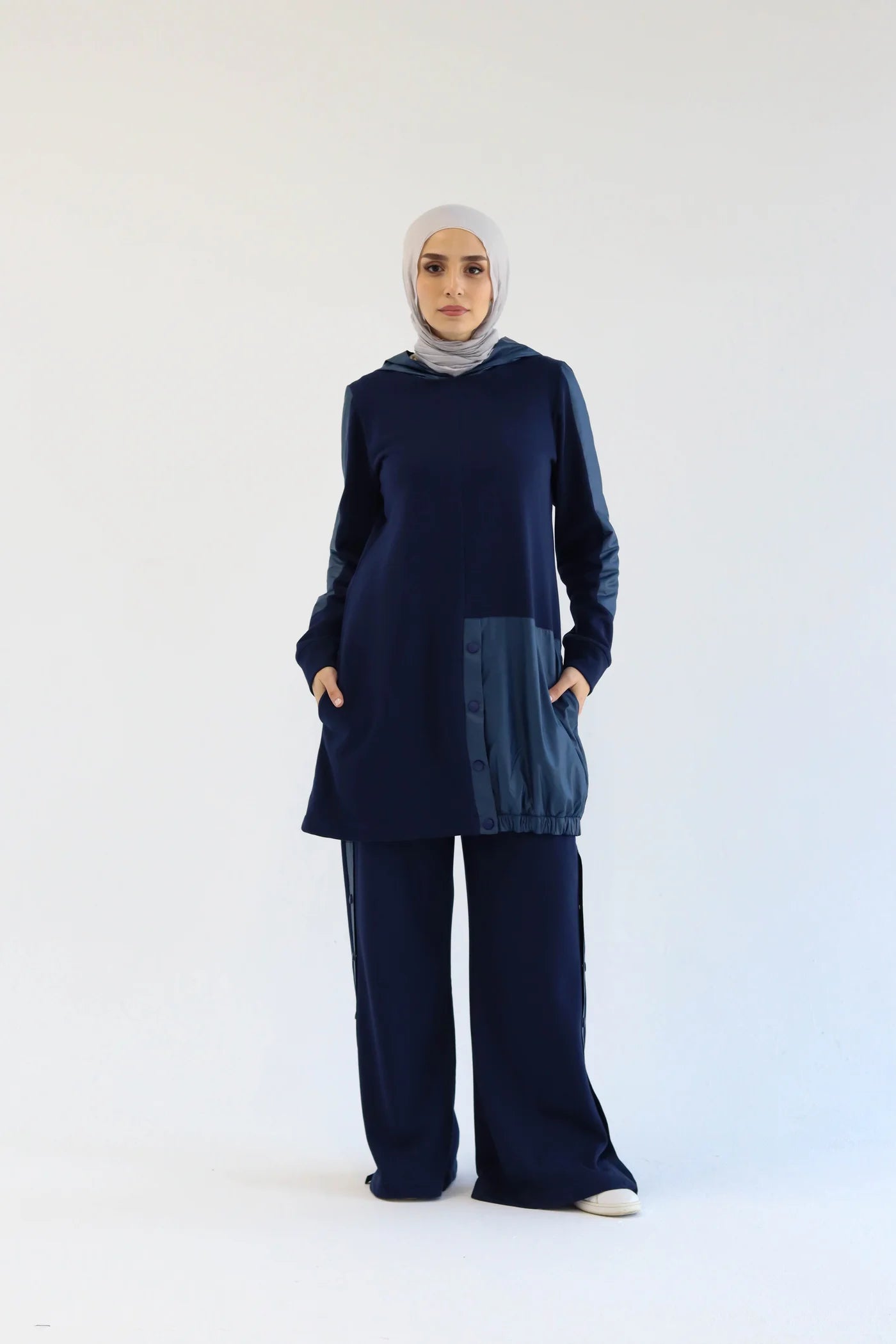 Woman wearing a navy blue outfit with a matching hijab on a white background