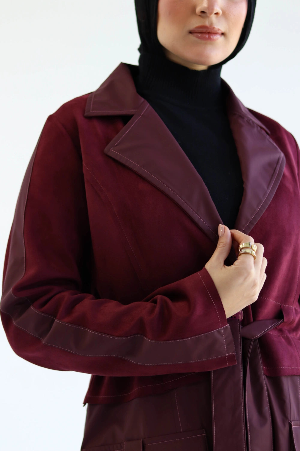 Woman wearing a burgundy Long suede trench coat with waterproof finish styled for modest winter layering with a white background
