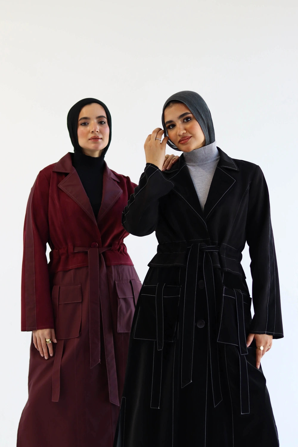 Two women wearingLong suede trench coat with waterproof finish styled for modest winter layering, one in red and the other in black, on a white background.