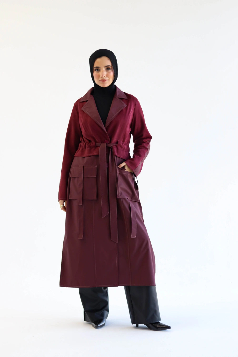 Woman wearing a long burgundy coat on a white background