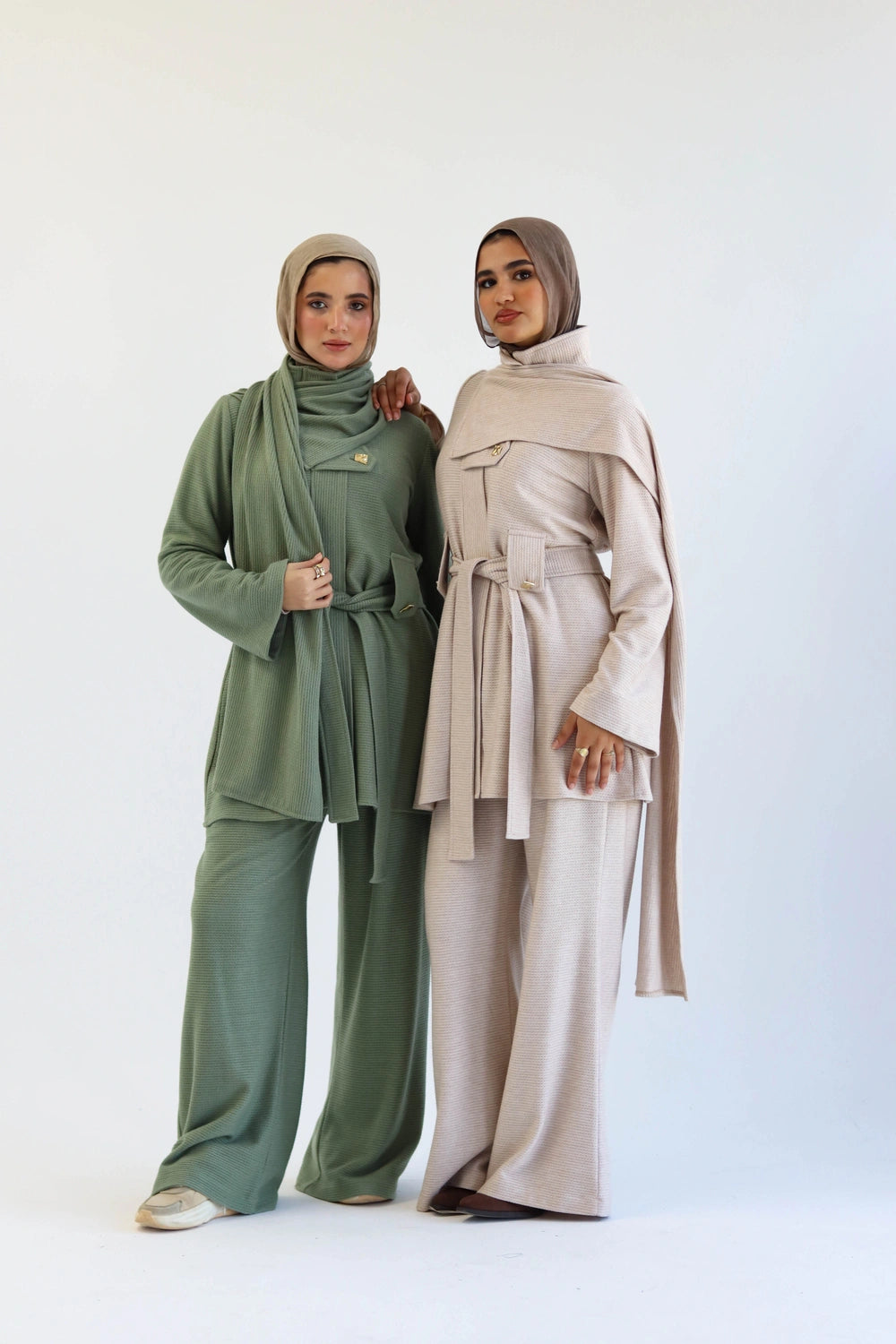 Two women wearing hijabs and modern clothing on a white background