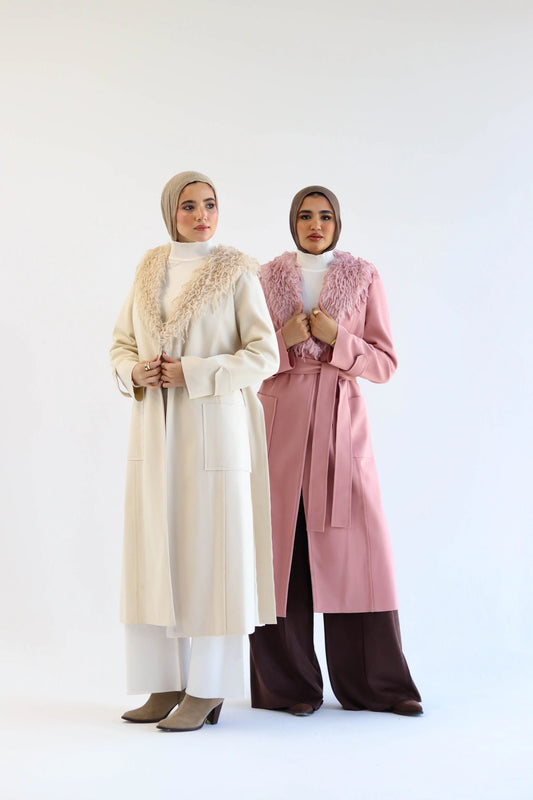 Two women wearing long wool coats with fur collars on a white background