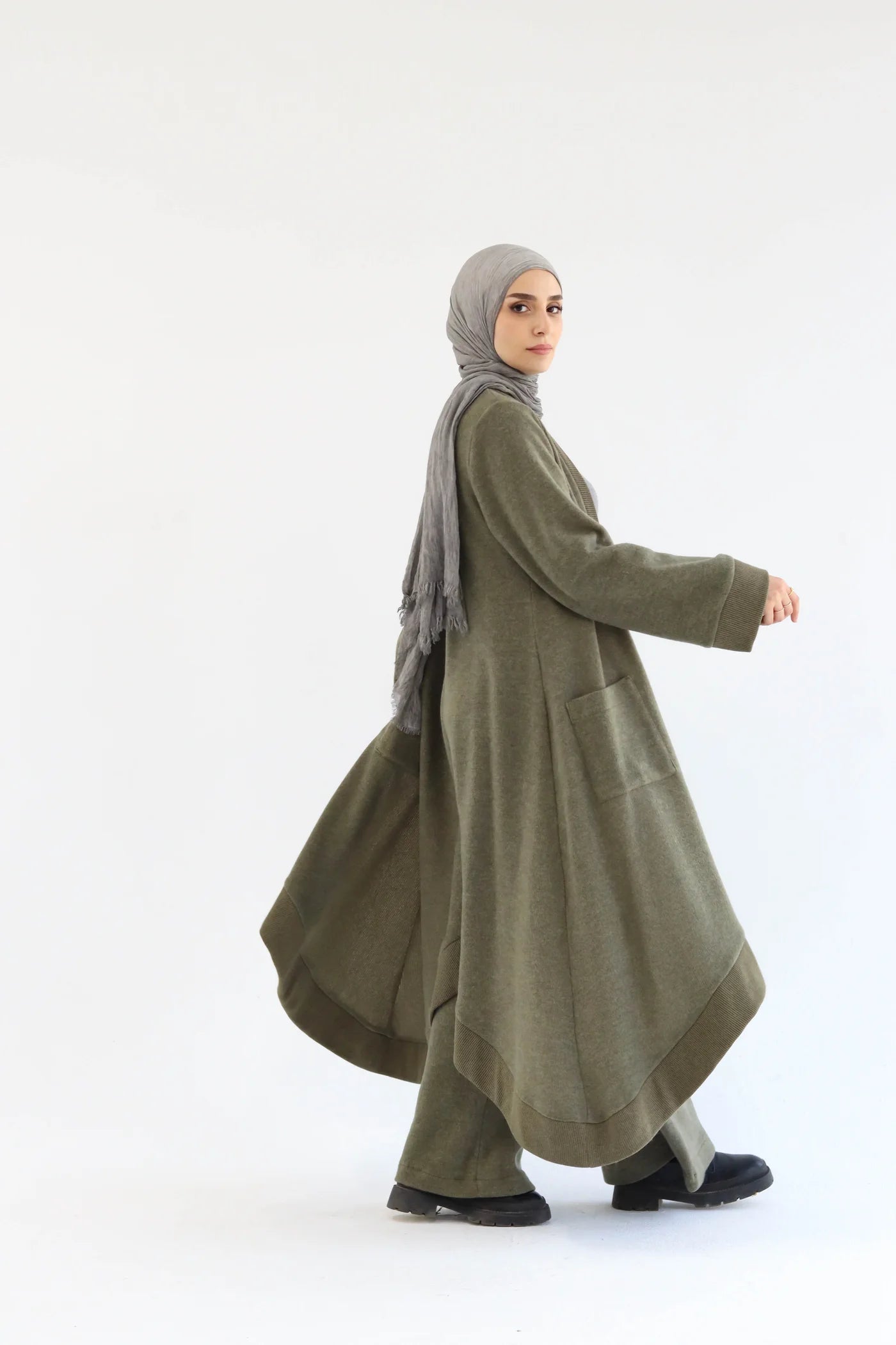 Side view of olive cardigan set highlighting layered silhouette and flowing knit fabric.
