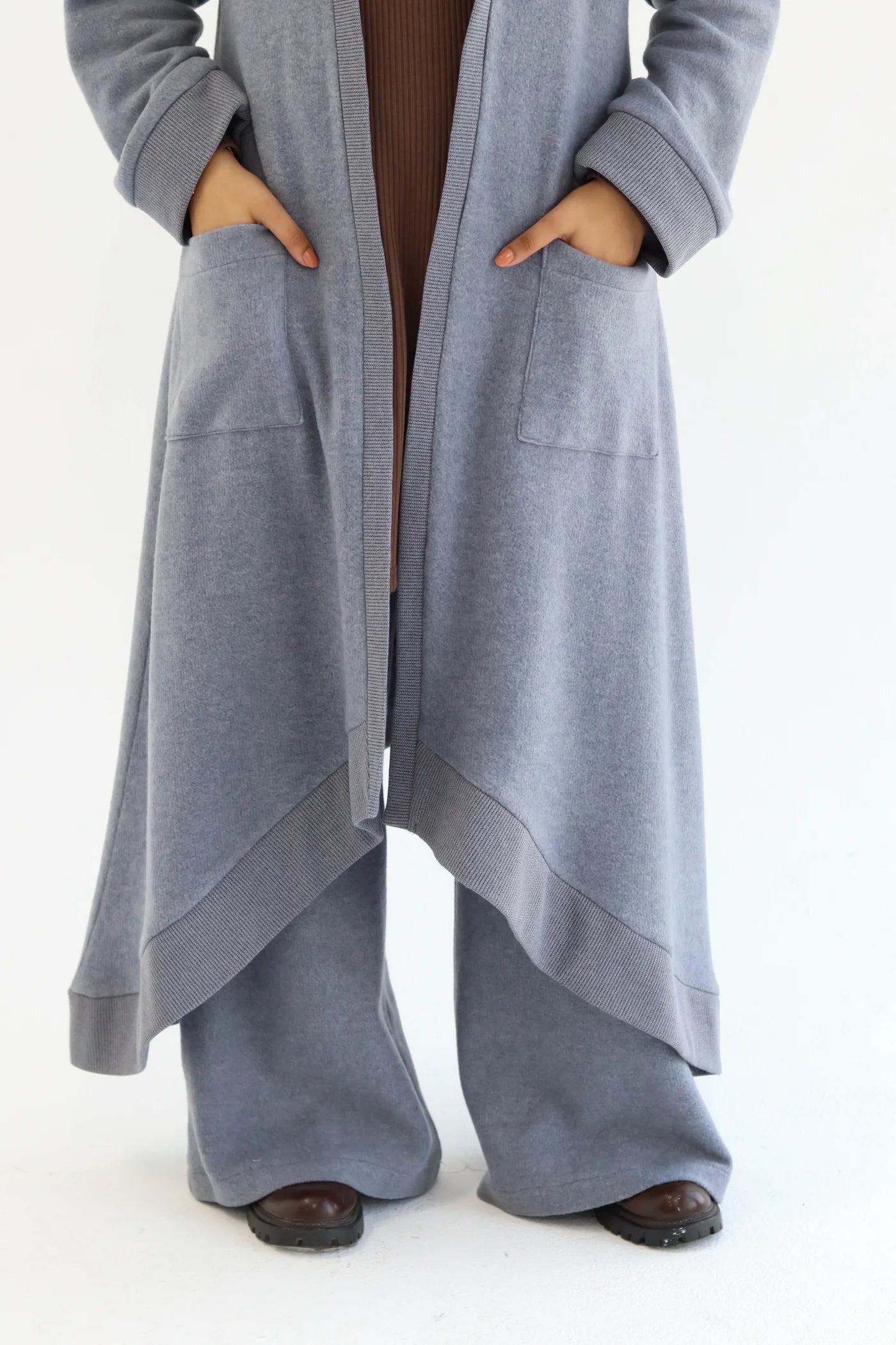 Blue cardigan set detail showing open-front overlap and wide-leg pants from waist level.
