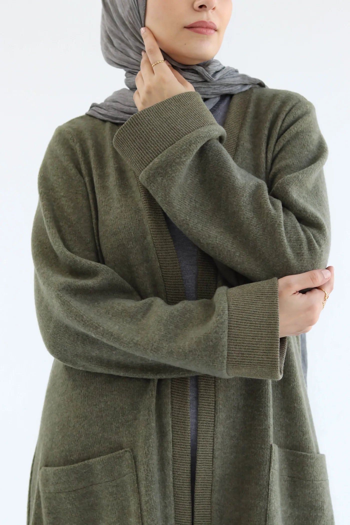 Olive green knitted cardigan set close-up highlighting soft texture, long sleeves, and relaxed collar area.