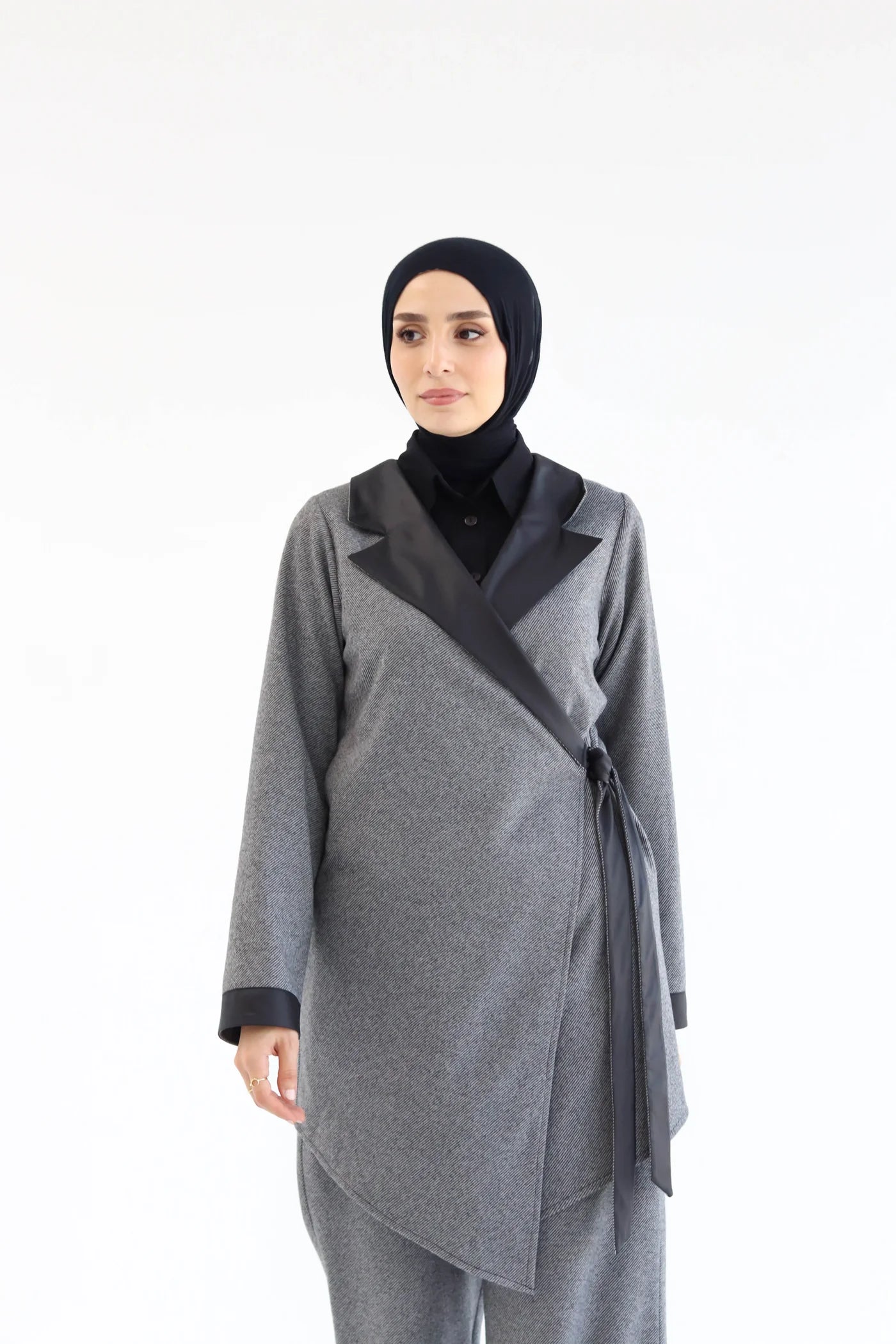 Woman wearing a gray outfit with a black hijab on a white background