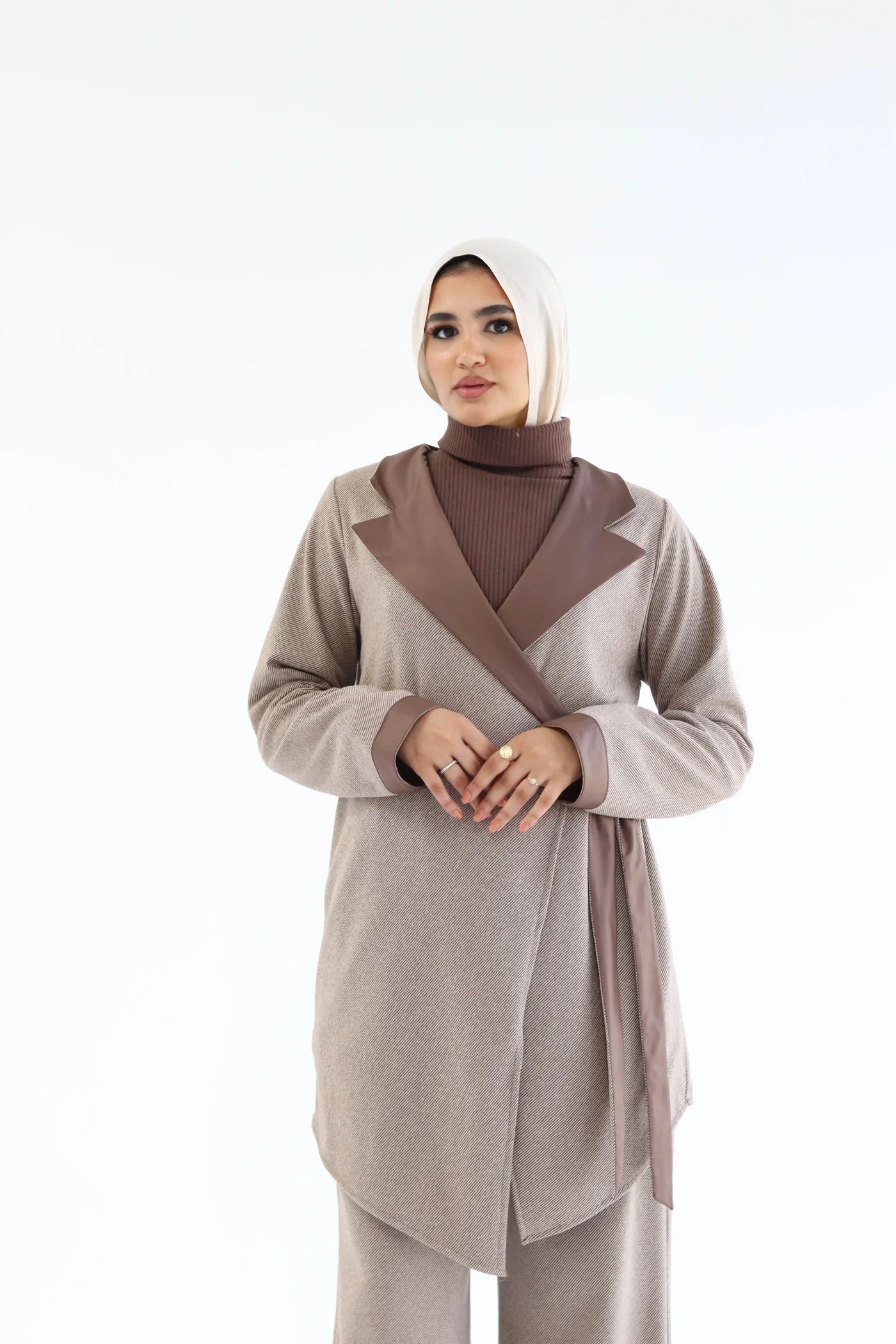 Woman wearing a beige outfit with a brown top on a white background