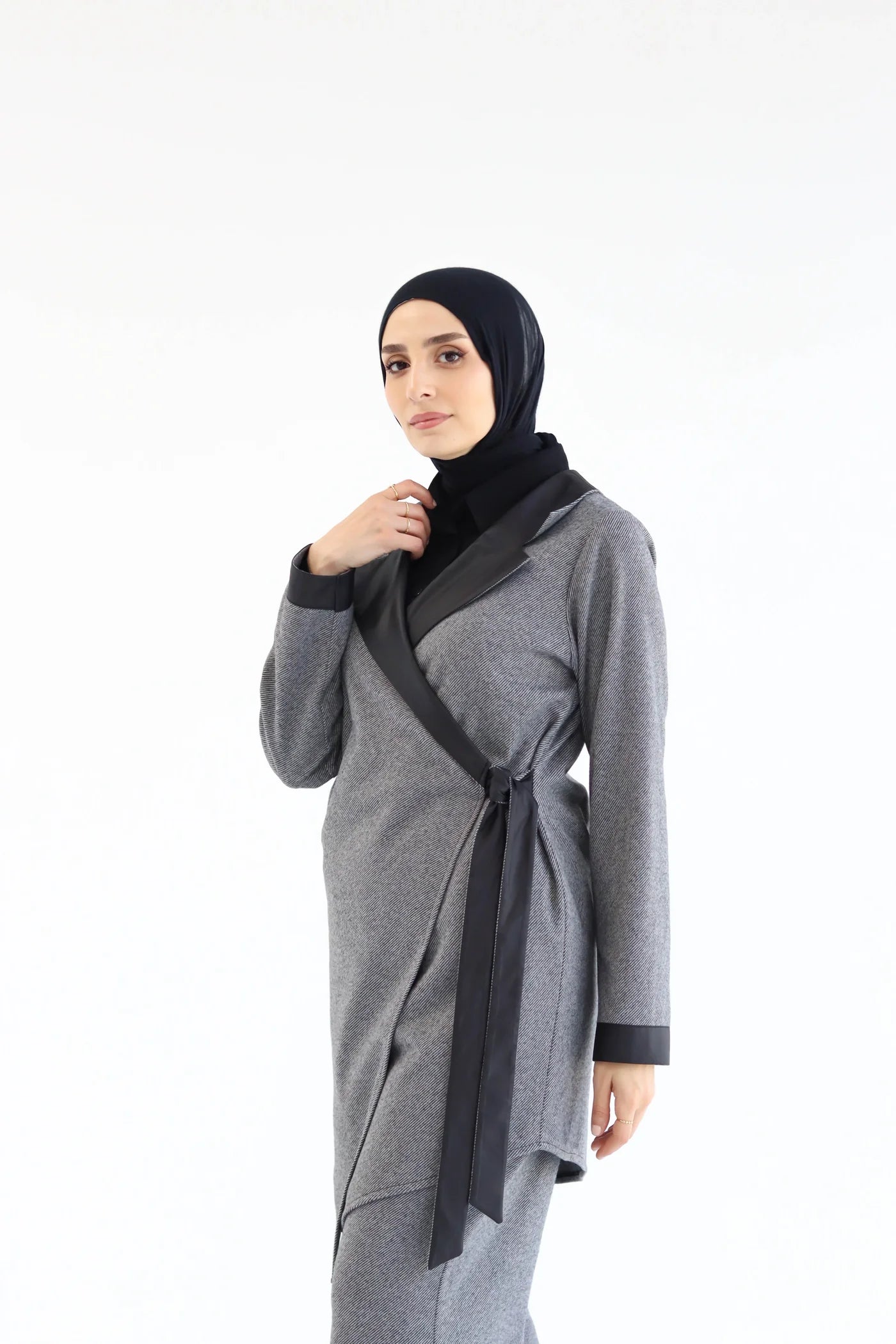 Woman wearing a gray cardigan with black accents on a white background