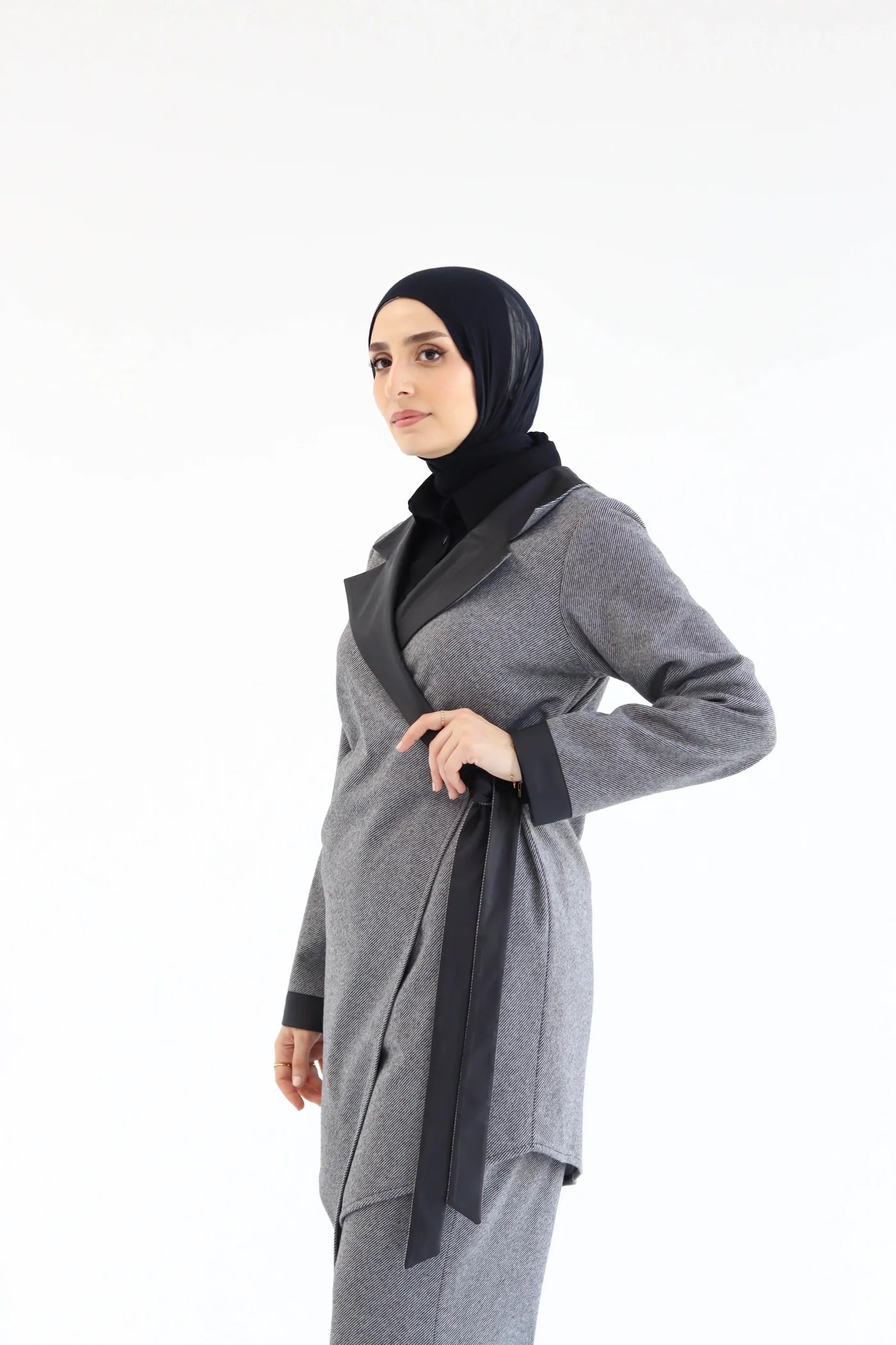 Woman wearing a gray cardigan with a black hijab on a white background