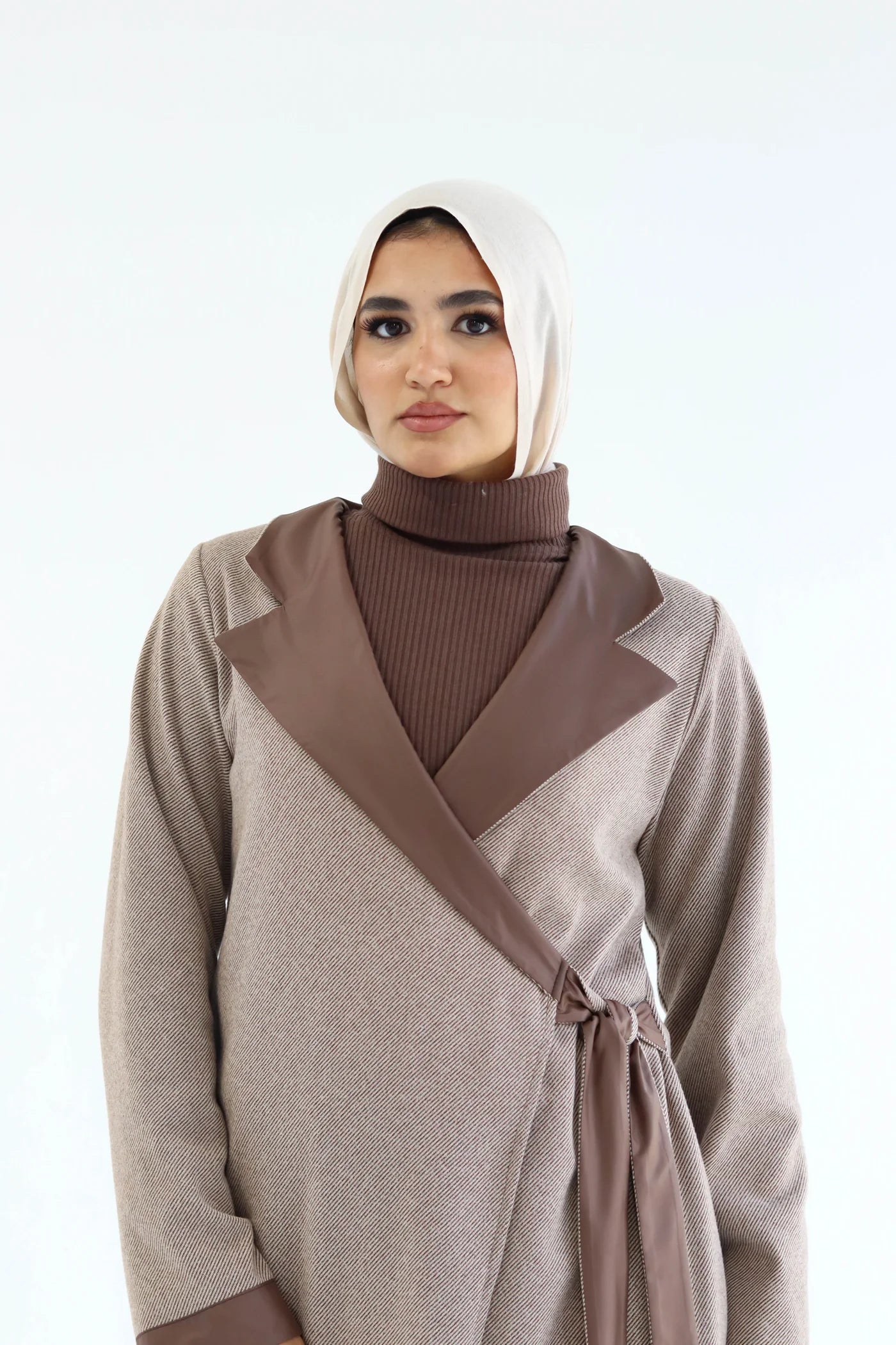 Woman wearing a beige and brown elegant cardigan with a matching hijab on a white background