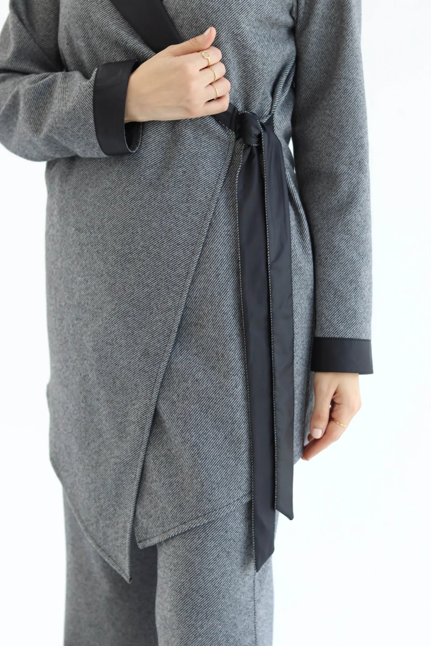 Gray wrap-style cardigan with black trim on a white background