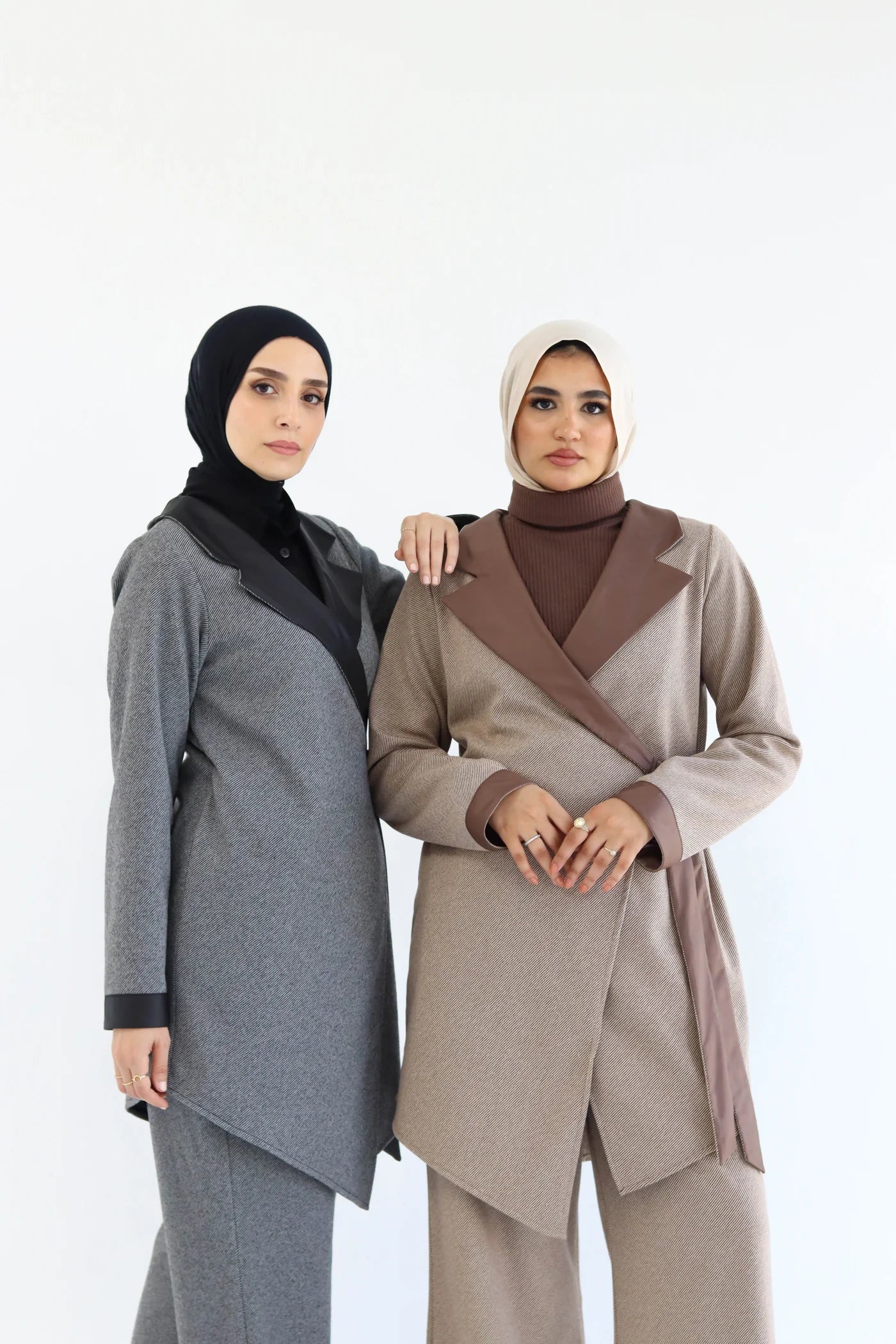 Two women wearing hijabs and elegant cardigans  on a white background
