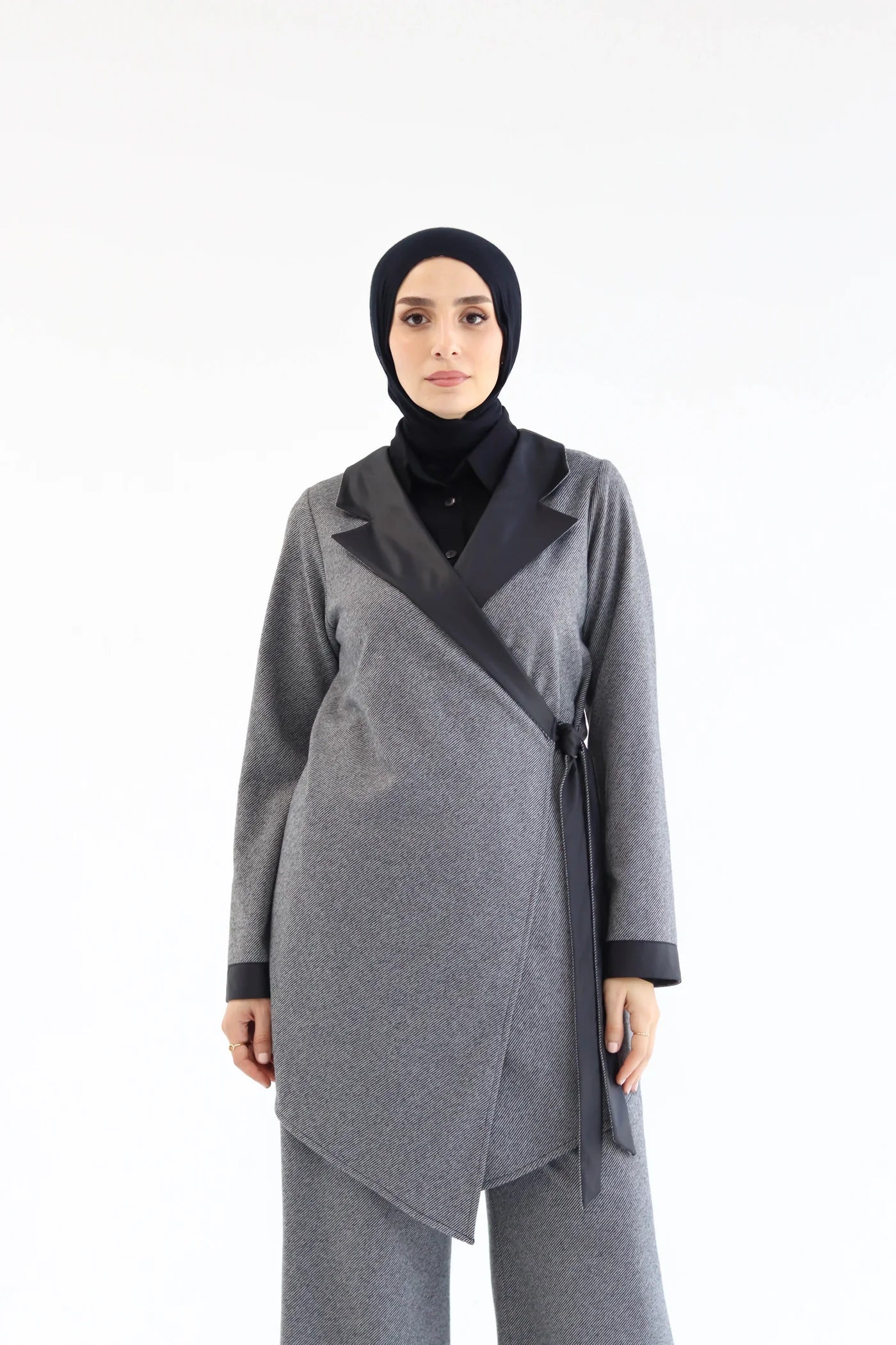 Woman wearing a gray outfit with a black hijab on a white background