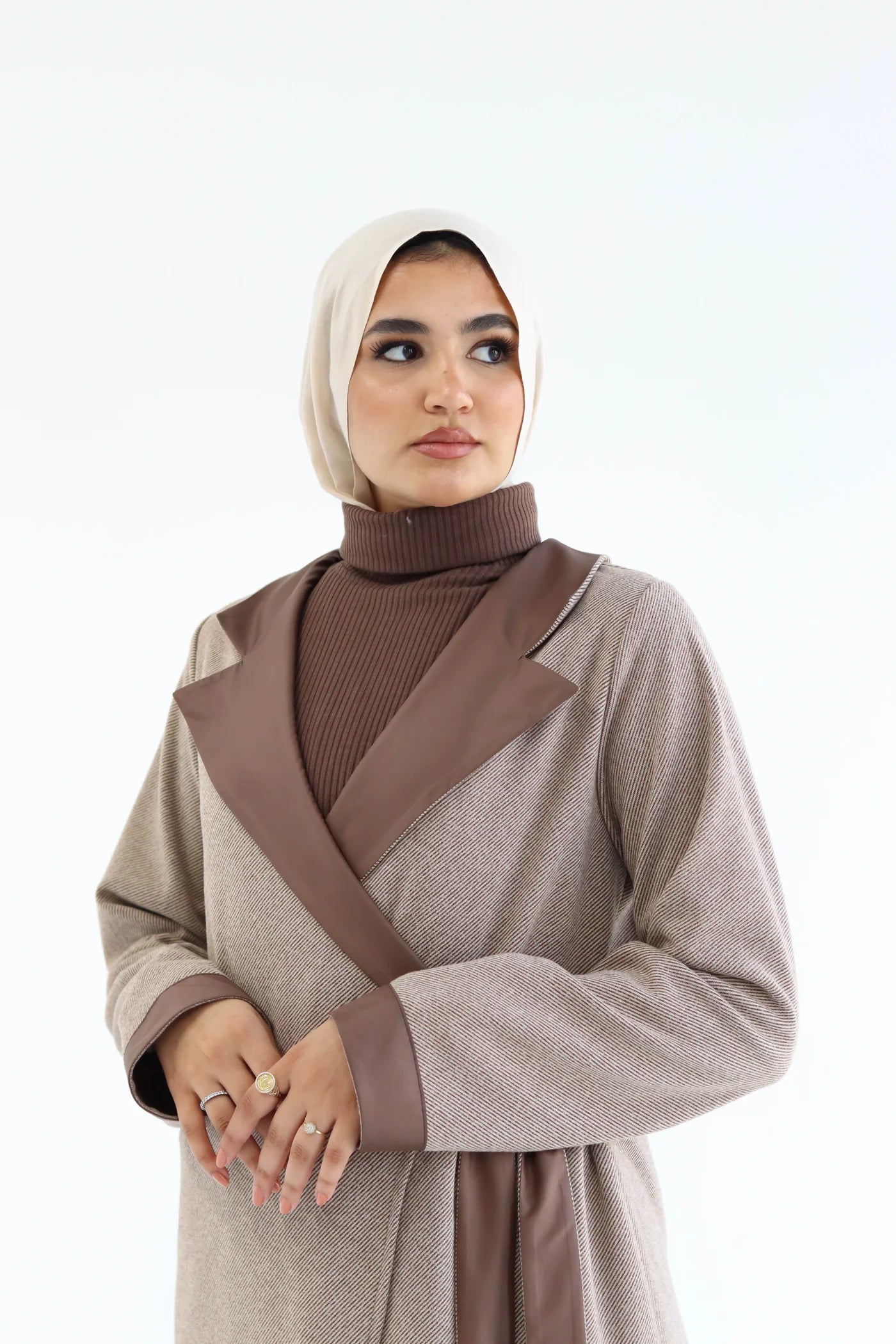 Woman wearing a brown and beige outfit with a hijab on a white background