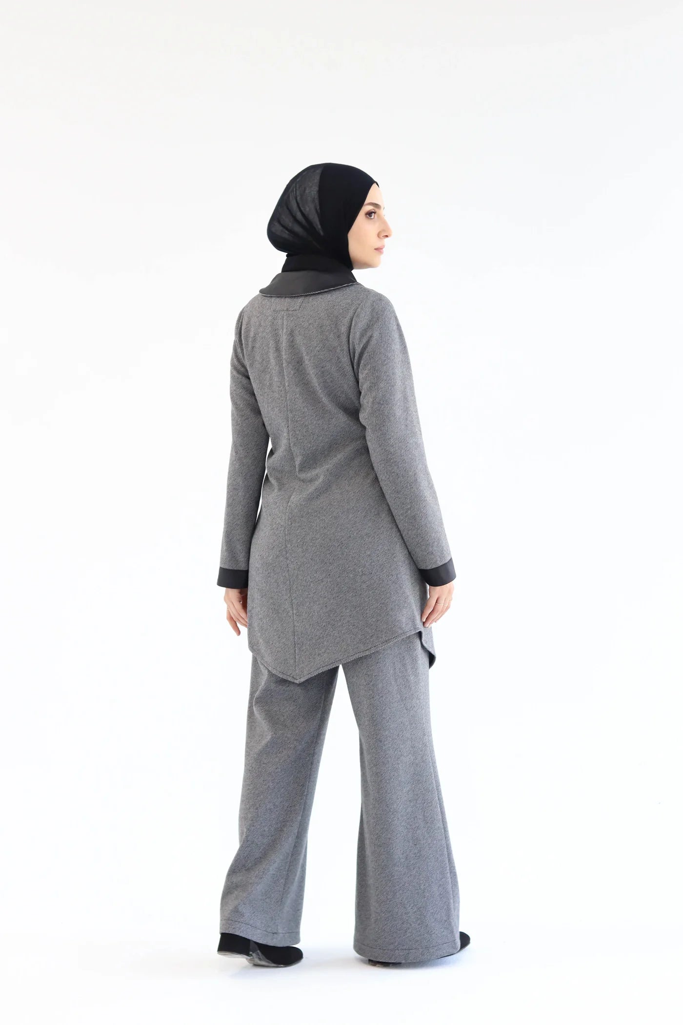 Woman wearing a gray outfit with a black hijab on a white background