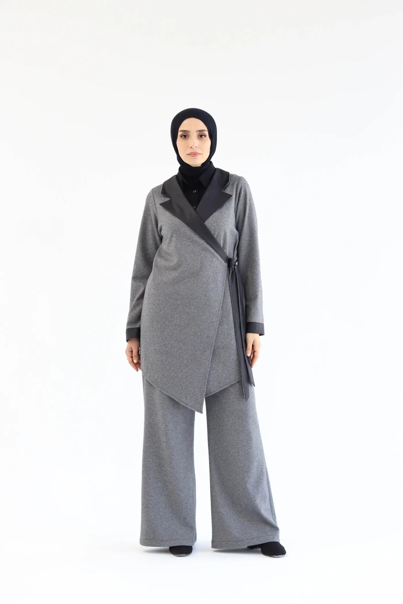 Woman wearing a gray outfit with a black hijab on a white background