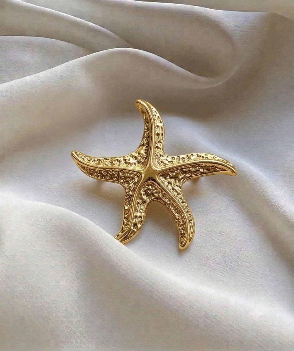 Gold-tone textured starfish brooch on ivory fabric